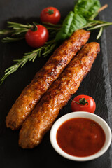 lula kebab with sauce and tomatoes on a dark background.