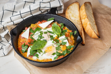 Fried eggs in a pan with vegetables and herbs.
