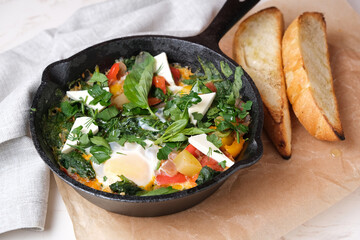 Fried eggs in a pan with vegetables and herbs.