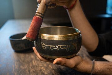 Fototapeta na wymiar Side view of young man's hands using Tibetan bowl