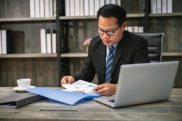 businessman working in the office. using laptop and taking notes on paper