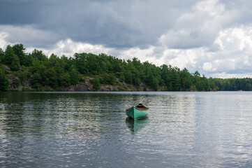 Obraz premium Green canoe tied to the shoreline on a lake in Muskoka - Ontario, Canada