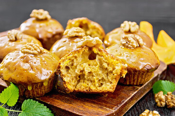Cupcake pumpkin with orange glaze and walnuts on wooden board