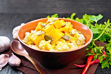 Porridge millet with spicy pumpkin in clay bowl on black board