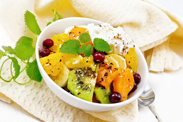 Salad fruit with cranberries and cream in bowl on wooden board