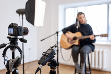 A young girl plays the guitar, recording video and sound.