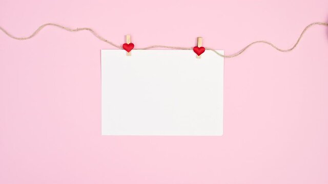 White paper hanged on rope with heart clothespin on bright pink theme. Stop motion