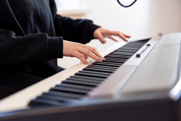 Fototapeta premium Female hands play musical keys, soft focus.