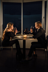 Romantic dinner for two couple drinking red wine, date at home at night at the table, Valentine's day celebration, man and woman relationship
