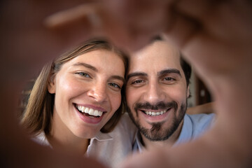 Happy excited married couple portrait with hand heart shaped frame. Young man and woman in love...