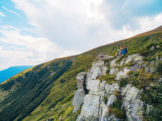 Aerial view of the Great Green Ridge. Guy and Girl Sitting on a Big Hill against the Backdrop of a Huge Mountain Landscape