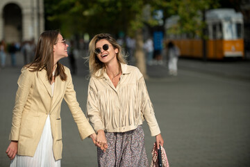 Laughing Girls with expressing positive emotions walking on the city street. Travelling in europe, budapest city. Funny vacation, romantic travel.