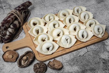 The process of making home-made dumplings. Raw homemade dumplings on a wooden board. Molding dumplings.