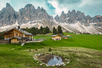 Alpine wooden chalets on the green fields, Dolomites, Italy