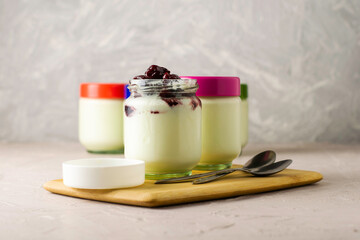 a jar of yogurt with cherry jam on a cutting board next to other jars of yogurt
