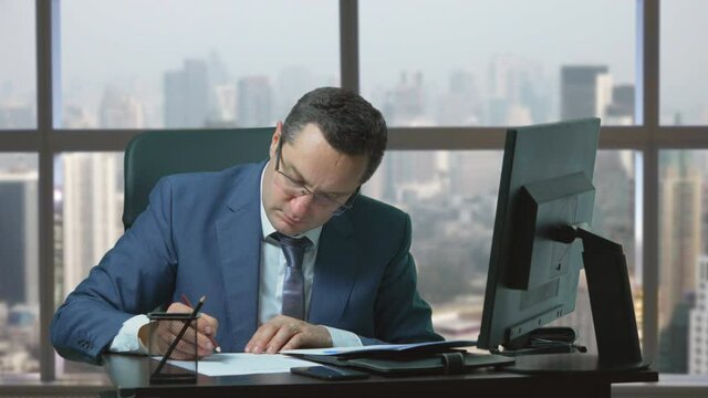 Concentrate man with suit sit desk at office and underline on paper, city view