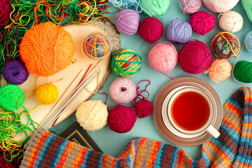 Lots of yarn and tea. Colorful knitting yarns and a cup of tea create a cozy atmosphere. Knitting is a kind of needlework.
