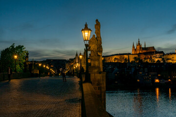 Fototapeta na wymiar lamp on Charles Bridge on Vltava River and in the background Prague Castle and St. Vitus Cathedral in the center of Prague at sunset in the evening Cer in the early evening