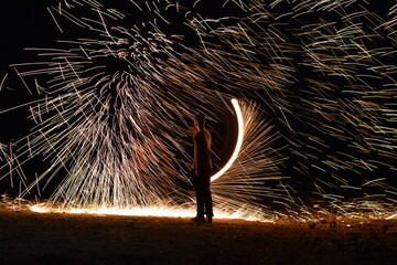Iron wool circle drawing light fireworks. Burning Steel Wool spinning, Trajectories of burning sparks at night. Movement light effect, steel wool fire hoop. long exposure light painting, Pyrotechnic
