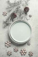 Obraz na płótnie Canvas Winter table setting with empty plate, fir branches , decoration snowflakes and pine cones on pale grey table. Top view with copy space. Frame