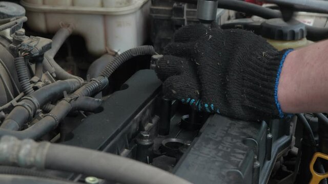 a man installs spark plugs on a dusty car engine. car repair. servic