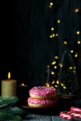 Donuts with colored caramel powder and pink icing on the background of Christmas decorations.
