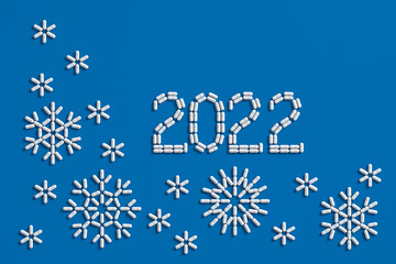 A pattern of many pills scattered on a blue background in the form of figures 2021. 3D illustration