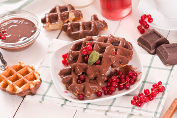 Waffles with chocolate topping, red currant and hazelnuts.