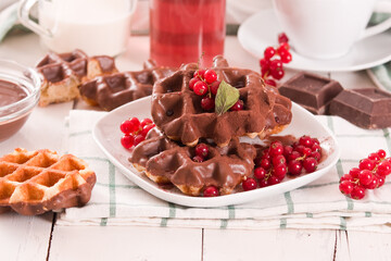 Waffles with chocolate topping, red currant and hazelnuts.