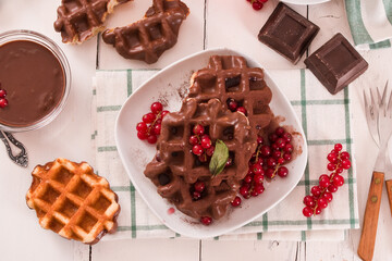 Waffles with chocolate topping, red currant and hazelnuts.