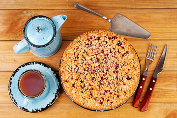 Homemade raspberries pie with streisel and cup of tea on wooden table. Top view.