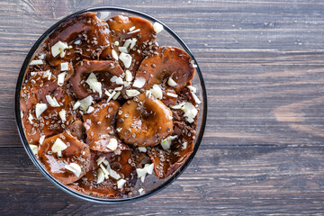 Sliced preserved mushrooms in bowl on table.Marinated mushrooms with pepper and bay leaf. Top view.Natural vegetarian food from the forest.