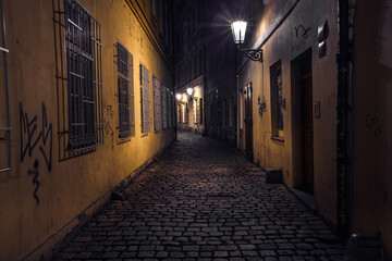 Fototapeta na wymiar view of a dark and illuminated cobblestone street in the old town of prague at night 2021