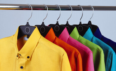 colorful shirts on hangers. linen shirts of different colors hung on black hooks on aluminum tube, shirts of vibrant colors on aluminum rack. concept clothing store. shirts for men, shirts for summer 
