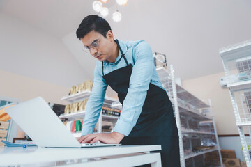 Businessman owner staff using computer laptop checking product inventory shelf in grocery store