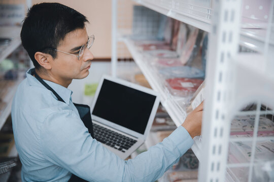 Businessman owner staff using computer laptop checking product inventory shelf in grocery store