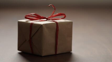 brown paper gift box with red bow on wood table