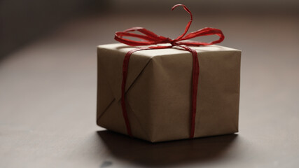 brown paper gift box with red bow on wood table