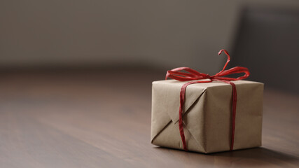 brown paper gift box with red bow on wood table