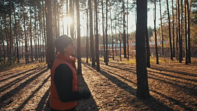 Young woman jogging on trail in autumn forest at sunrise. Slow motion 4k.