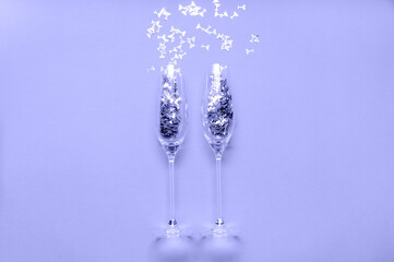 Champagne Glasses with Confetti colored in trendy color of year 2022 Very Peri. Creative Christmas Concept