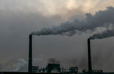 Fuming chimneys of the plant against the background of gray smog from emissions into the environment. Ecological concept.