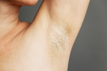 Hair in the armpits of a woman. Taking care of yourself. Close-up. Gray background.