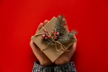 Woman's hands hold christmas DIY present. Present box on red background, top view, copy space