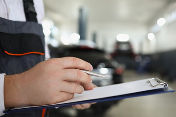 Male service worker fill maintenance documentation after fixing car - obrazy, fototapety, plakaty
