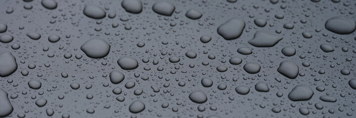 Fototapeta na wymiar Closeup of raindrops on dark glass background