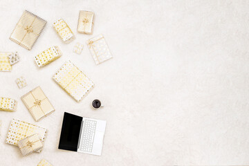 Christmas. Online shopping. Laptop among the many wrapped gifts in white gold wrapping paper on the snow white carpet . Top view. Concept