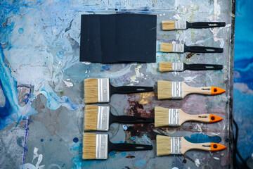 Flat lay top view of brushes for painting on a messy stained table