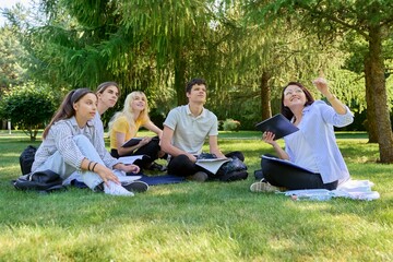 Outdoor, group of students with female teacher sitting on grass