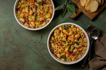 Pasta e fagioli is a typical dish of traditional Italian cuisine made with short pasta and beans, with celery, carrot, onion, and sage Top table view.